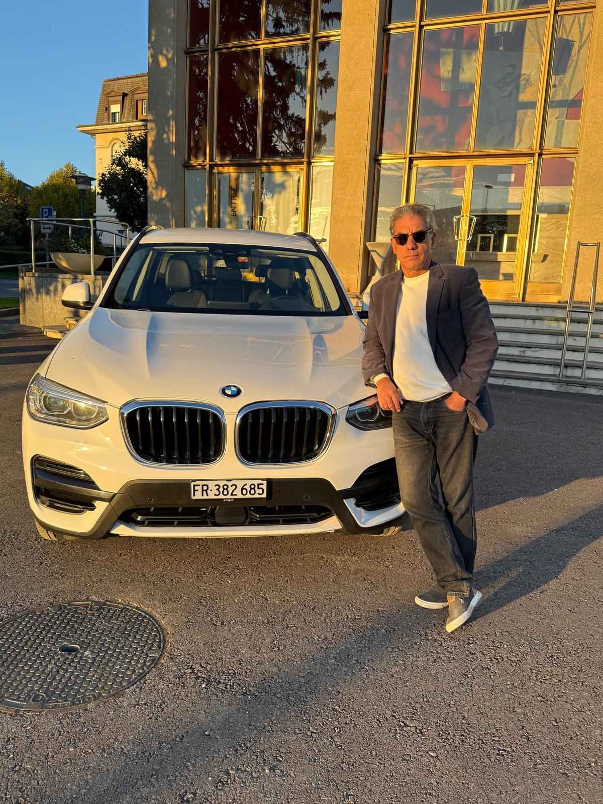 Chauffeur TransLife Tour devant son véhicule au coucher du soleil