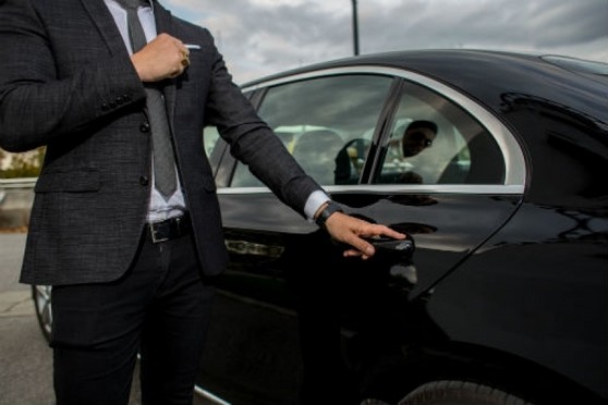 Chauffeur en costume à côté d'une voiture